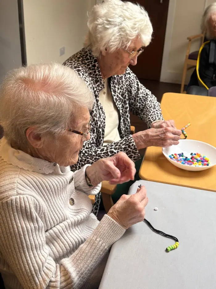 Residents making beaded bracelets at a table