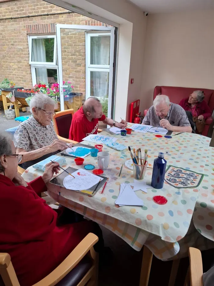 Residents painting together around a large table by the garden doors